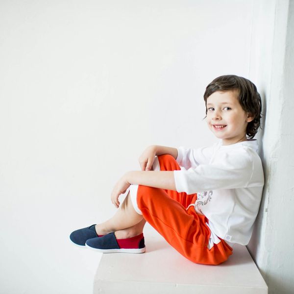 Happy child doing a simple yoga pose in a bright room.